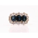 A 20th century sapphire and diamond ring, the three oval cut sapphires within a surround of eighteen