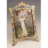 A French porcelain plaque, late 19th century, depicting a classical maiden beneath a prunus tree,