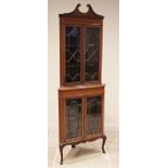 An Edwardian mahogany freestanding corner display cabinet, with a swan neck pediment over a