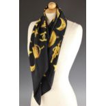 A Chanel silk scarf, the black scarf designed as gold charms and 'CC' logos, 89cm x 86cm, along with