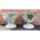 A pair of reconstituted stone garden urns, of cup form, moulded in relief with rings united by