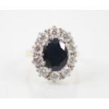 An Edwardian style sapphire and diamond cluster ring, the central oval cut sapphire claw set in