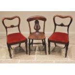 A pair of early Victorian rosewood dining chairs, each with a compressed balloon back, carved