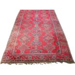 A Turkish wool carpet, in vibrant red, blue and green colourways, the central field with multiple