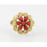An untested coral and yellow metal dress ring, the seven spherical corals beads designed as a