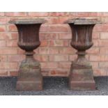 A pair of Victorian cast iron garden urns, of campana form, with a gadrooned rim and fluted body,