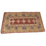 A Baluchistan wool rug, in red, sky blue and oatmeal colourways, the central red field with five