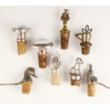 A selection of white metal mounted bottle stoppers, including a silver mounted example, indistinct