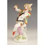A German porcelain figure of Pulcinella, 19th century, modelled standing on one leg holding a