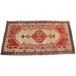 A Baluchistan wool rug, in red, blue and ivory colourways, the elongated central medallion, enclosed