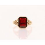 A garnet and 9ct gold ring, the emerald cut garnet within a milgrain setting edge, leading to