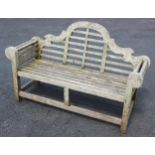 A Lutyens type hardwood bench, of typical slatted break arch form, upon supports of square