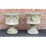 A pair of reconstituted stone garden urns, of campana form, moulded in relief with leaf and berry