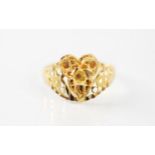 A yellow metal ring, the openwork head with applied cannetille style decoration with swirl detail,