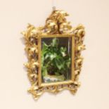 A giltwood Florentine wall mirror, 19th century, the scrolling leafy openwork crest and frame,