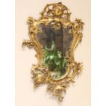A Louis XVI style rococo gilt metal wall mirror, 20th century, the shield shaped mirrored plate
