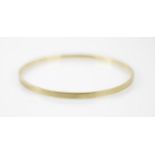An early 20th century 9ct yellow gold bangle, the bangle with engraved engine turned detail