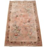 A Chinese Kayam silk pile rug, the pink ground with a mirrored floral design, within recurring
