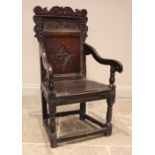 A 17th century oak Wainscott chair, the scrolled top rail over a lunette carved frieze, holly and