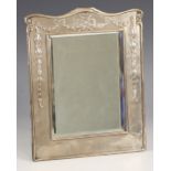 An Edwardian silver mounted mirror, William Neale, Chester 1908, the rectangular frame with embossed