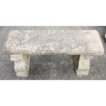 A reconstituted stone twin pedestal bench, the rectangular top upon shaped and scrolled supports,
