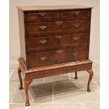 A George II walnut chest on stand, mid 18th century, the quarter veneered and crossbanded top over