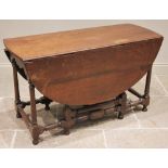 An 18th century oak drop leaf dining table, the oval top over a shaped apron upon ring turned