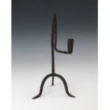 A wrought iron rush light and candle holder, 18th century, of typical scissored form on an arched