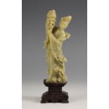 A Chinese carved soapstone figure of Lan Caihe, late 19th century, modelled standing supporting a