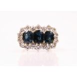 A 20th century sapphire and diamond ring, the three oval cut sapphires within a surround of eighteen