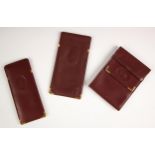 A Cartier burgundy leather wallet, with slip fastening enclosing card and cash compartments to the