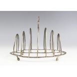 A George III silver toast rack, Henry Green, London 1794, the circular thumbpiece above seven arched