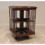 An Edwardian walnut revolving bookcase, the square moulded top over two tiers, enclosed by lath side