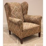 A ladies wingback armchair, early 20th century, in geometric foliate fabric, the shaped wingbacks