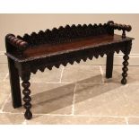 A Victorian carved oak window/hall seat, the shaped back rest carved with recurring flowerheads,