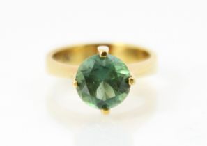 A yellow metal and green tourmaline set dress ring, the round cut tourmaline set in high four claw