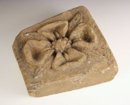 Two medieval style carved stone corbels, the first relief carved with a flower head upon a