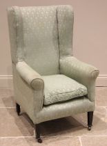 A George III style wingback fireside armchair, late 19th/early 20th century, upholstered in a