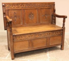 A golden oak monks bench, early 20th century, the back rest with a carved scrolling foliate frieze