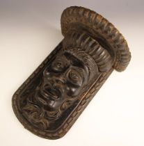 An Eastern European carved and stained walnut mask wall bracket, 17th/18th century, the male mask