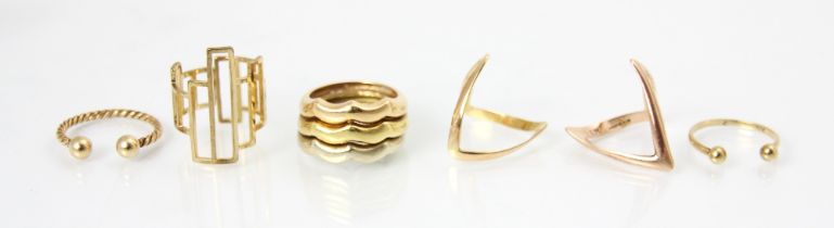 A selection of six yellow metal and gold coloured rings, including a plain polished stylised
