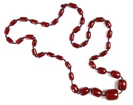 A string of cherry coloured 'amber' beads, the graduated barrel shaped beads strung upon red string,