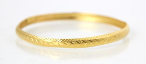 A yellow metal bangle, the grooved and engraved detailed bangle with ‘7AS22’ applied pad, 10gms