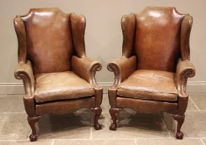 A pair of George III style tan leather wingback armchairs, late 20th century, each with a shaped