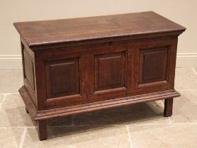 An 18th century oak coffer, the hinged cover over three inverted panels and a moulded apron, upon