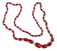 A string of cherry coloured 'amber' beads, the graduated barrel shaped beads with plastic screw