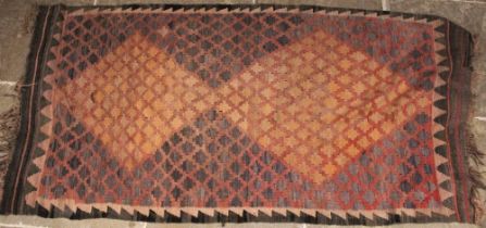 A kilim rug, the two central lozenges formed with an arrangement of geometric terracotta guls,