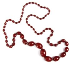 A string of cherry coloured 'amber' beads, the graduated beads strung upon string, largest bead 2.