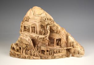 A Chinese pink soapstone carving, late 19th century, modelled as a mountainside with houses,
