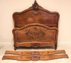 A French Louis XV style walnut bed, early 20th century, the quarter veneered shaped headboard with a